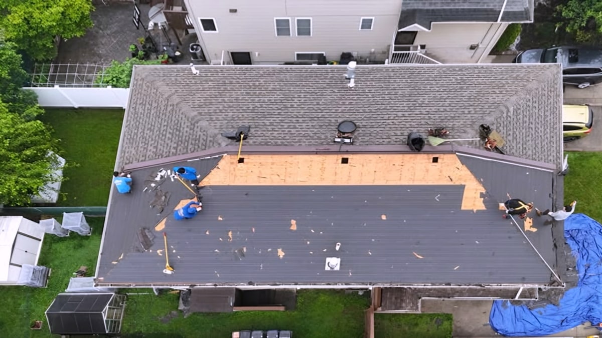 Aerial view of crew tearing off shingles on a residential roof